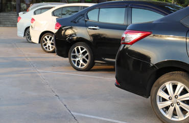 Closeup of rear, back side of black car with  other cars parking in outdoor parking area in sunny day. 