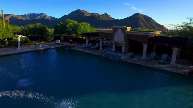 smooth and low aerial flight over a balcony and across pool in the desert mountains