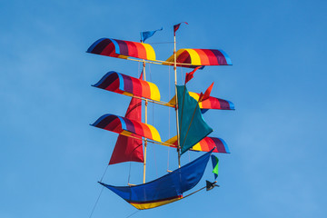 flying ship - rainbow colored kite flies on the blue sky