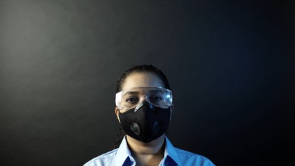 Woman in urban protective or medical mask with glasses, looking at the camera on black background....