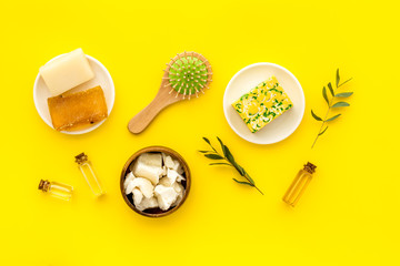 Cosmetics for hair care with argan and jojoba oil on yellow background top-down