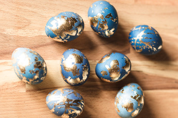 Blue easter eggs decorated gold patel on wood background.