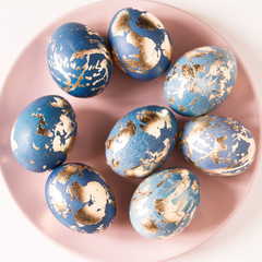 Blue easter eggs decorated gold patel on the pink plate.