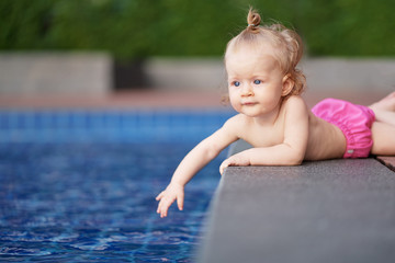 Fototapeta na wymiar Little baby girl near swimming pool outdoors.