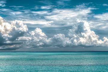 Calm ocean of turquoise color water and above it are huge dramatic cloud of type Cumulus during the...