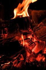 Obraz premium three burning billets in hot stove.Fire flame burning coal and wood in fireplace.Hot coals in the fire.Flames of a campfire in the night.Toned image