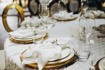festive banquet tables are decorated with compositions of flowers, candles and figures of golden birds, on the tables are plates, glasses, napkins and cutlery