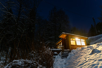 Shining wooden cottage in the mountains with snow.