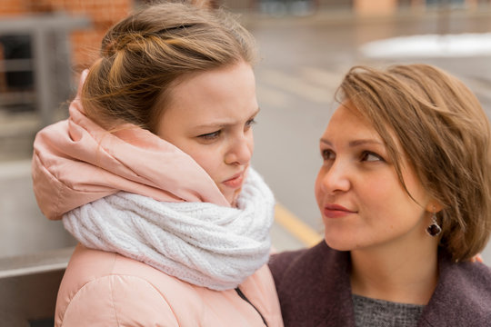 mother and daughter look at each other, the girl makes a displeased face. intergenerational relationship, conflict of parents and children