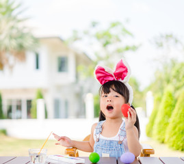 Cute little asian toddler girl wearing bunny ears on Easter day.Little asian Girl painting easter...