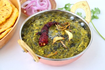 Sarson ka saag and Makke di roti. mustard leaves curry. its a popular punjabi winter dish made using corn meal & mustard leaves. served with onions and green chili in copper vessels. with copy space.