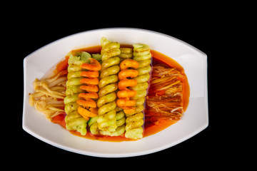 vegetables sliced spiral with spicy Chinese sauce on a black isolated background