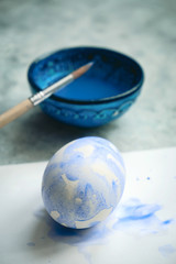 Fototapeta na wymiar selective focus bowl with blue dye, brush painted eggs, painting eggs for Easter diy concept