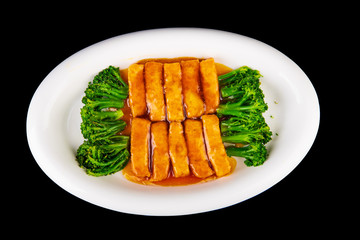 fried tofu in sauce with broccoli on a black isolated background