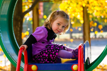 A girl plays in the playground in the fall. Bright, autumn sunny day.