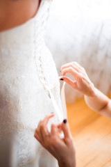 Bridesmaid tying bow on wedding dress.