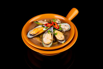 mussels with spicy broth with green pepper on a black background