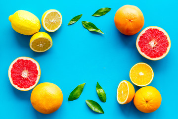 Citrus fruits frame - halfs of lemons, grapefruits, leaves - on blue background top-down copy space