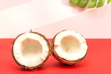 Two halves of fresh raw coconut  on red backgound with light shadows in white.