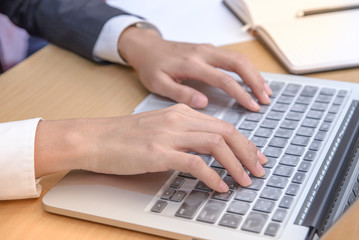 Female hand typing on laptop keyboard in office