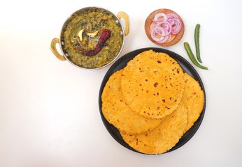 Sarson ka saag and Makke di roti. mustard leaves curry. its a popular punjabi winter dish made using corn meal & mustard leaves. served with onions and green chili in copper vessels. with copy space.