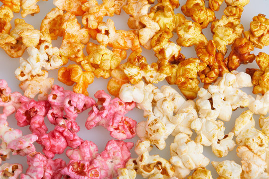 Different flavors of popcorn (cherry, caramel, salted, cheese tastes), close up background. Snacks and food for a movie wathcing