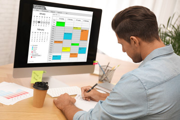 Fototapeta na wymiar Man planning his schedule with calendar app on computer in office