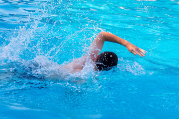 Young guy swims in the pool. Rest at the resort_
