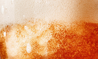 Close up gold background texture of yellow lager beer with froth and bubbles in glass, soft focus