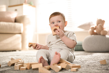 Cute baby playing with wooden blocks at home