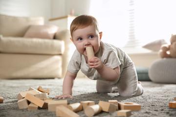 Cute baby playing with wooden blocks at home