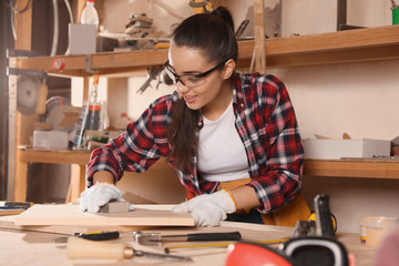 Naklejka na ściany i meble Female carpenter polishing wooden board in workshop