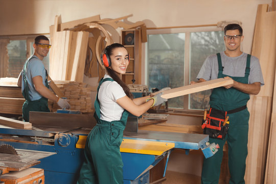 Professional carpenters with wooden plank in workshop