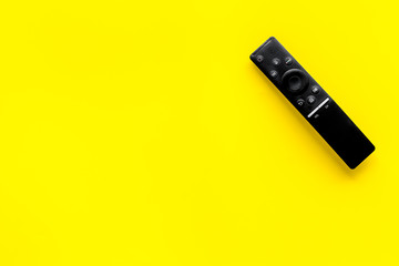 Television air recording concept. TV remote on yellow background top-down copy space