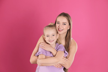 Happy mother and little daughter on pink background