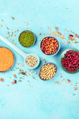 Various legumes flat lay. Different pulses, shot from above on a blue background with a place for text. Red beans, lentils, chickpeas, soybeans, and black-eyed peas