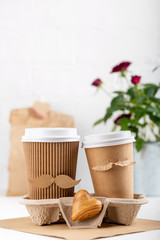 Two paper cups of coffee in cardboard tray on white background. Take out food. Cups with face of...