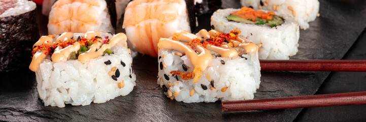 Sushi set close-up panorama with chopsticks on a black background