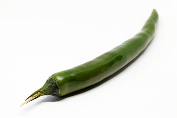 a whole green chili fruit against white background