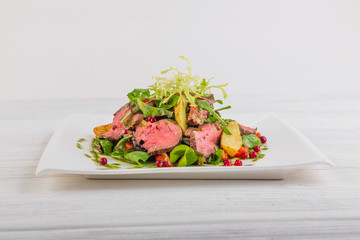salad with potatoes and roast beef with green salad on a white wooden background
