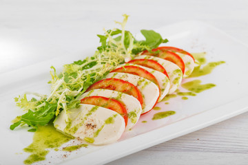 caprese with pesto on a white wooden background