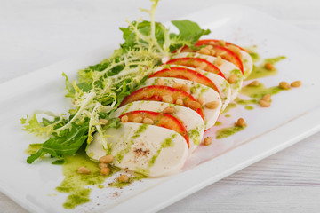 caprese with pesto on a white wooden background