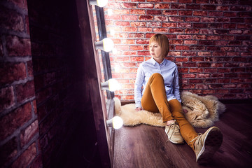 Girl in shirt in front of a lighted mirror in a dark room. Model posing for a photo shoot in the...
