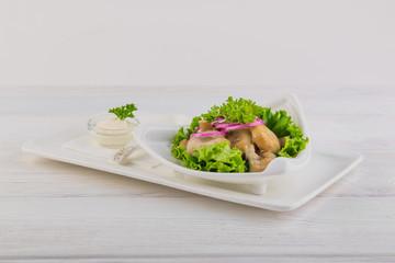 salted mushrooms with onions and sour cream on white wooden background