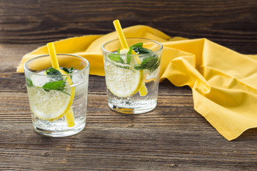 Lemonade or mojito cocktail with lemon and mint with ice. Cold summer refreshing drink decorated with yellow napkin