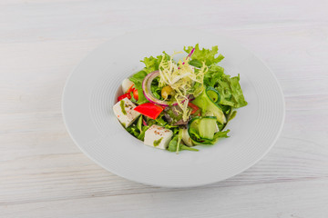 Greek salad on white wooden background