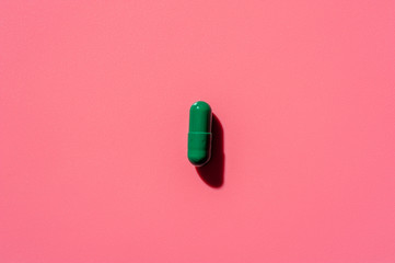 Close-up of one pill lies on a pink surface