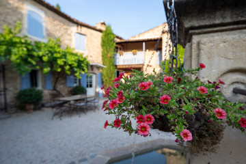 Hanging baskets on a fountain in the courtyard of a typical house in Provence, France