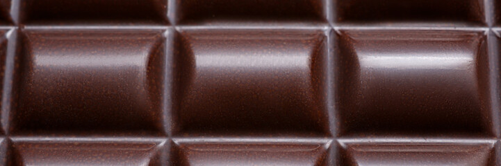 Close-up of yummy dark chocolate bar melt in peculiar form of round shape tile made of bitter cocoa beans. Brown delicacy emanating tempting sugary smell