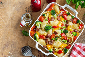 baked vegetable and sausages lumaconi pasta in white baking dish